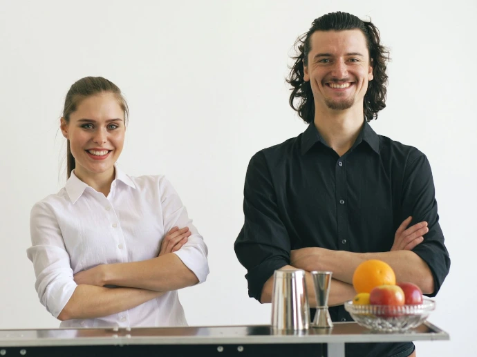 Three smiling bartenders standing behind a bar